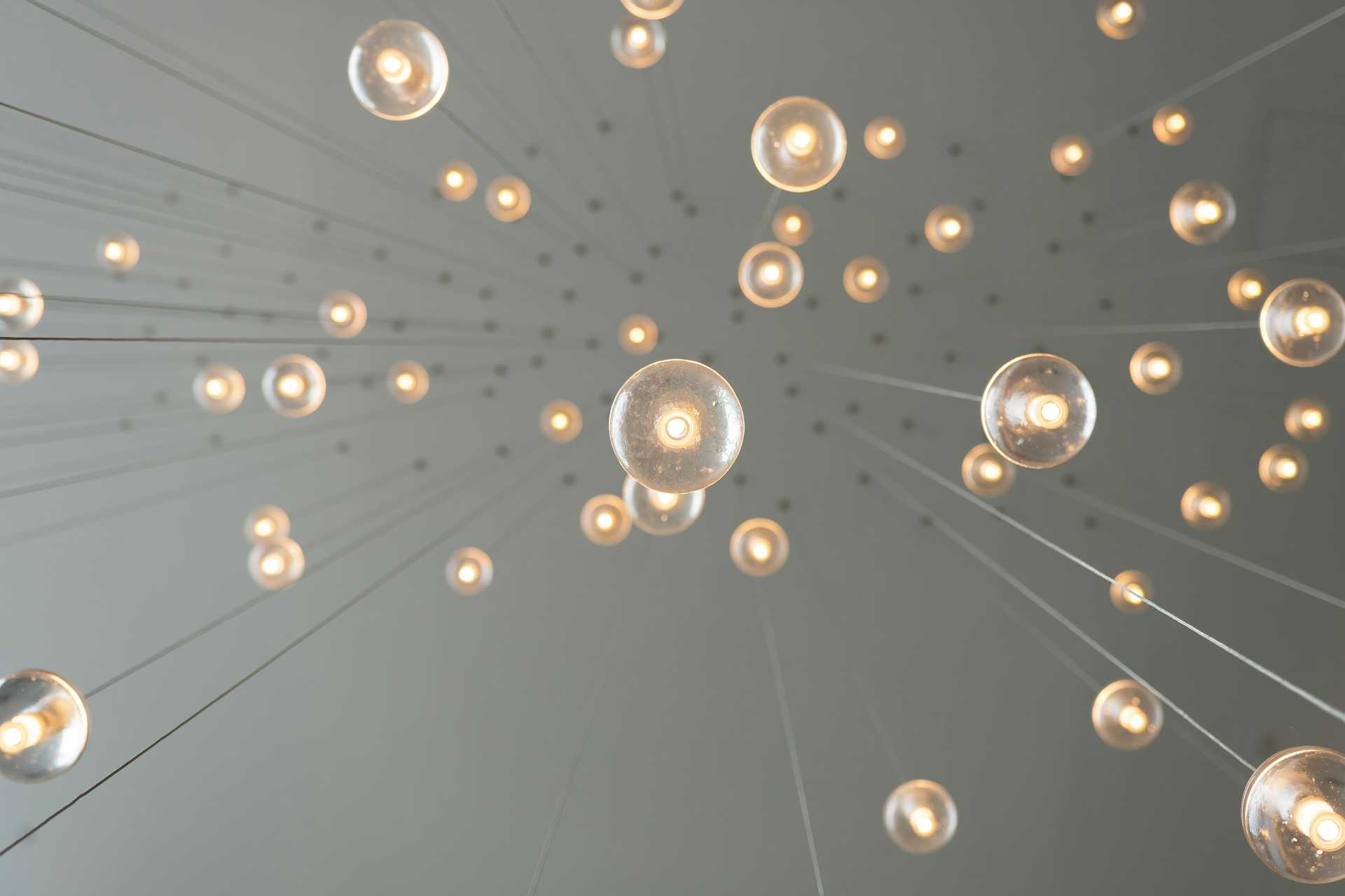 Display of multiple glowing light bulbs suspended from the ceiling, symbolizing innovative ideas and inventions.