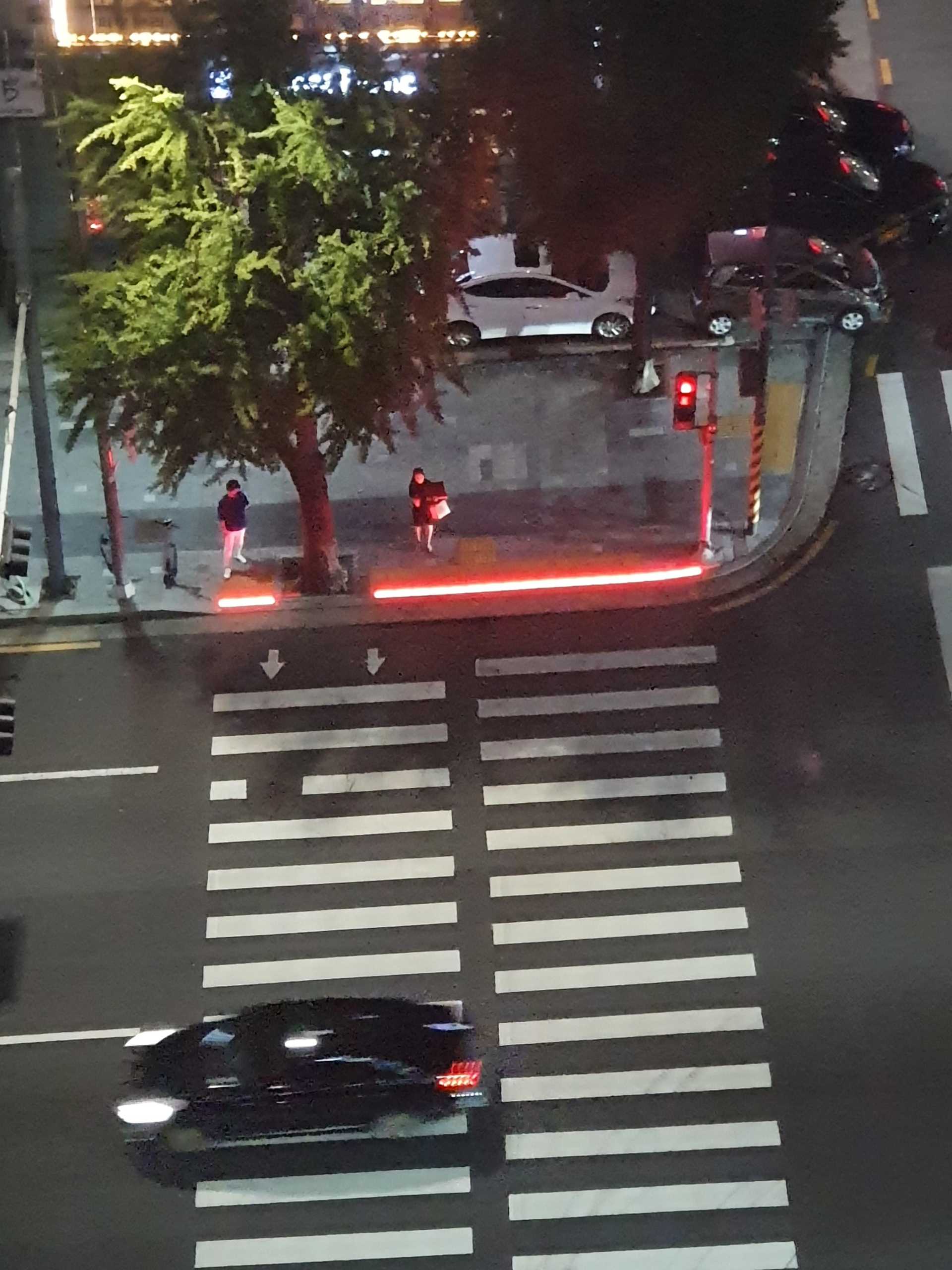 Looking down on a crosswalk in a Korean city with an illuminated safety light to alert phone users when they step off the curb.